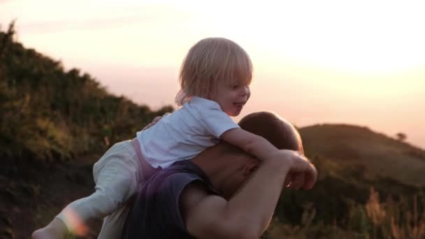 Father sits his son on his shoulders at sunset in the mountains. High quality 4k footage - Filmagem, Vídeo