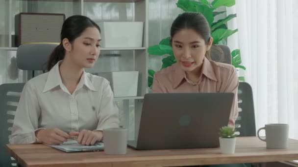 Two young enthusiastic businesswoman working together in the office workspace. Young colleagues having discussion and using laptop together. Modern office workers sitting together at desk. - Footage, Video
