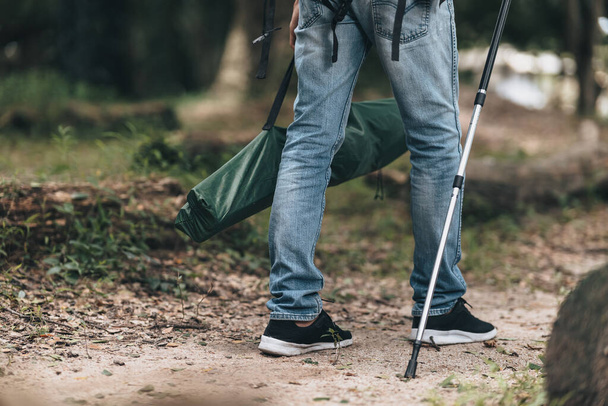 Hikers use trekking pole with backpacks and hold tent bag walking through the forest. hiking and adventure concept. - Фото, изображение