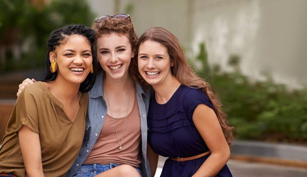 Time together is just never quite enough. Three beautiful young women smiling happily as they sit outside - Foto, Bild