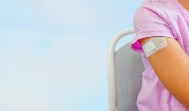 Το παιδί δείχνει το χέρι του με ένα γύψο μετά το εμβόλιο. Αντιγραφή χώρου. Έννοια εμβολιασμού και ανοσοποίησης. - Φωτογραφία, εικόνα