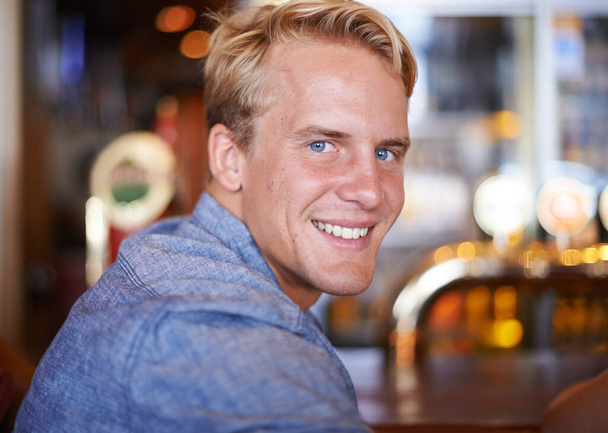 Keen for a pint. A portrait of a happy young man sitting in a pub - Fotoğraf, Görsel