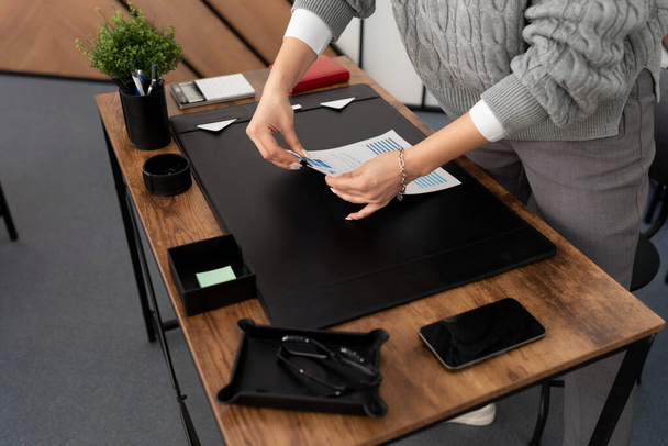 kobieta biznesmen przy jej biurku w biurze składa stos dokumentów. - Zdjęcie, obraz