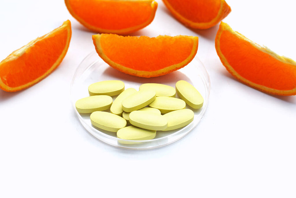 Vitamin C pilulky s pomerančovým ovocem na bílém pozadí. - Fotografie, Obrázek