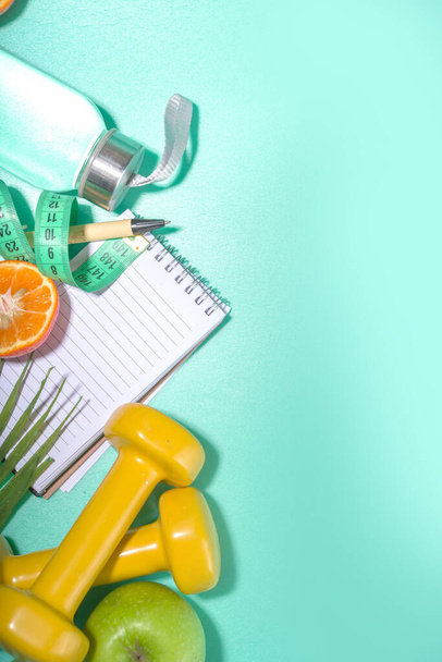 Spring, summer slimming season concept. Sport bottle with water, fitness dumbbells, beach lounger decor, measuring tape, notepad, apple, sliced orange on light blue white background. Flatlay copy space top view - Photo, Image