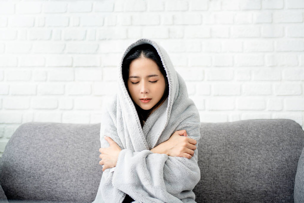 Close up sick asian woman covered with blanket sitting on couch, ill young female in warm suffering from fever, catch cold or flu, virus symptoms. - Foto, Imagem