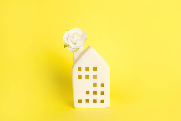 Miniature white toy house with flower on yellow background. Space for text - Fotografie, Obrázek