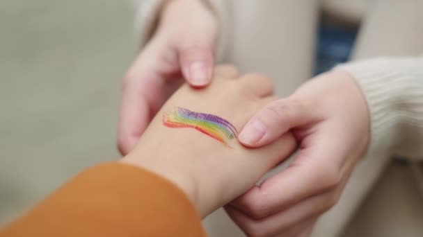 Close up slow motion video of asian lesbians touching each others hands painted with a lgbt flag - Materiał filmowy, wideo