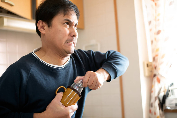 Man pulls out a stuck feeding bottle in a cup or mug.  - Zdjęcie, obraz