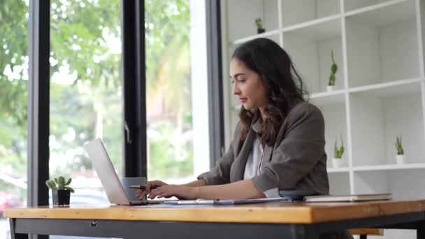 Asiatin sieht gestresst aus, während sie Laptop mit Finanzdokument auf dem Tisch benutzt. Frauen arbeiten von zu Hause aus. Hochwertiges 4k Filmmaterial - Filmmaterial, Video