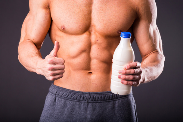 Bodybuilder houden een fles melk - Foto, afbeelding