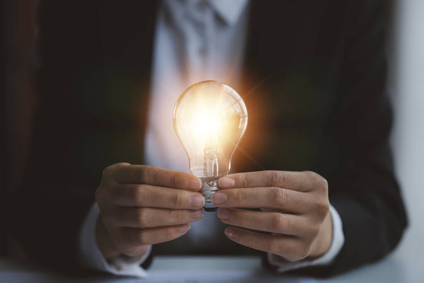 Person holding glowing lamp, Creative new idea. Innovation, brainstorming, strategizing to make the business grow and be profitable. Concept execution, strategy planning and profit management. - Fotó, kép