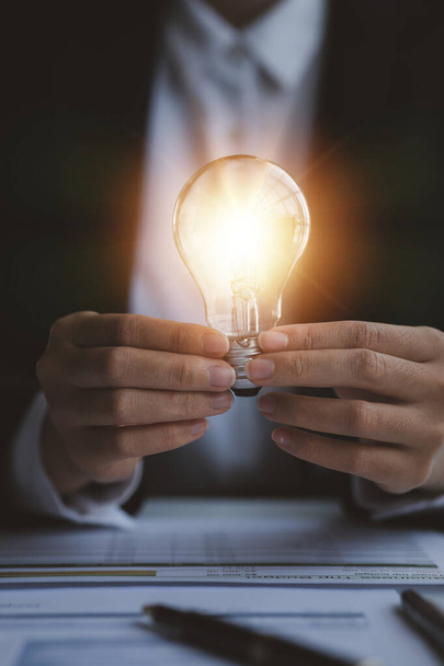 Person holding glowing lamp, Creative new idea. Innovation, brainstorming, strategizing to make the business grow and be profitable. Concept execution, strategy planning and profit management. - Photo, Image