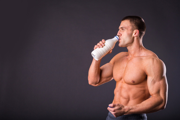 Bodybuilder holding a bottle of milk - Photo, image