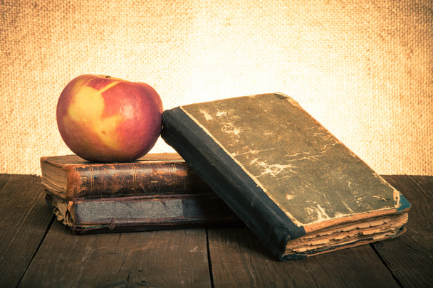 Still life with apple and a stack of old books on old wooden tab - Photo, Image