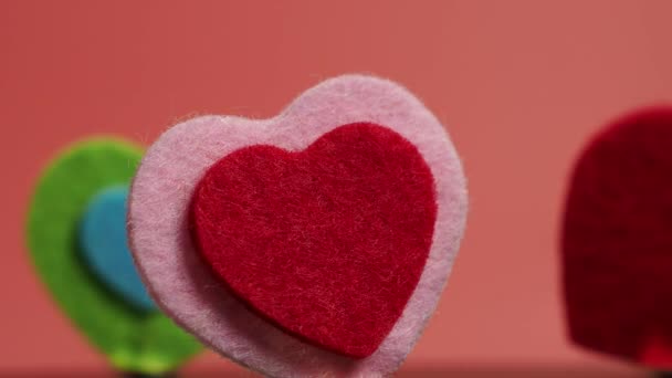 Obracające się serce w różnych kolorach na różowym tle. Koncepcja Walentynek. - Materiał filmowy, wideo