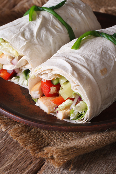 Burrito mit Huhn und Gemüse in Großaufnahme auf einem Teller. vertikal - Foto, Bild