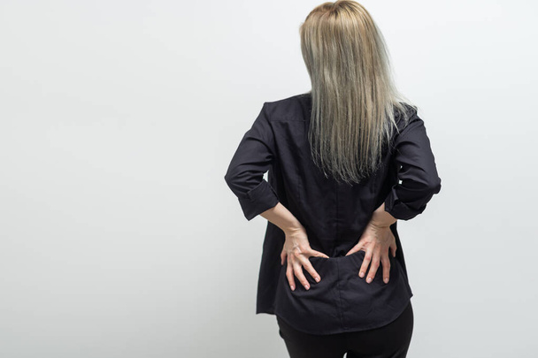Rückenschmerzen. Frau reibt sich die Muskeln ihres unteren Rückens. Sportverletzungen - Foto, Bild