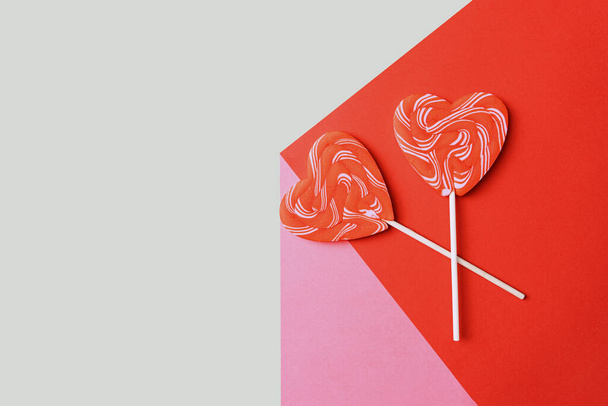 Love relationship, abstract minimalistic concept of love and affection. Two candy hearts for Valentine's Day. Traditional heart-shaped lollipops on a tricolor background, the illusion of volume - Foto, Imagen