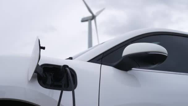 Fortschrittliches Zukunftskonzept für die Energieinfrastruktur: Elektrofahrzeuge werden an einer Ladestation aufgeladen, die mit grüner und erneuerbarer Energie aus einer Windkraftanlage betrieben wird, um die Umwelt zu schonen. - Filmmaterial, Video
