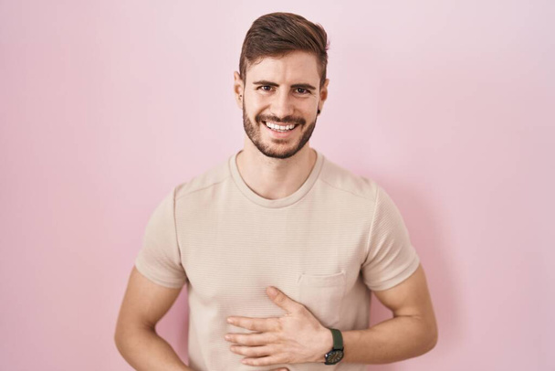 Uomo ispanico con la barba in piedi sopra sfondo rosa sorridente e ridente forte perché divertente scherzo pazzo con le mani sul corpo.  - Foto, immagini