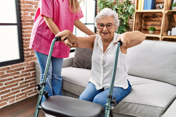 Paciente idosa de cabelos grisalhos, com suporte para enfermeiro e andador em geriatria - Foto, Imagem