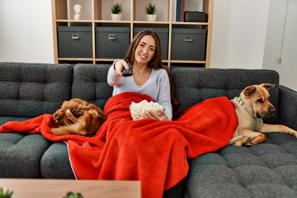 jonge latino vrouw kijken film zitten op bank met honden thuis - Foto, afbeelding