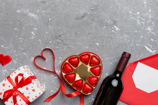 Pullo punaviiniä värillisellä taustalla Ystävänpäivä lahjapaketti, kirjekuori ja suklaa. Sydämen muotoinen lahja laatikko suklaata ylhäältä näkymä kopioi tilaa. - Valokuva, kuva