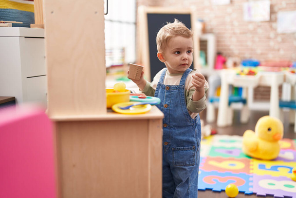 Adorable niño jugando con la cocina de juego de pie en el jardín de infantes - Foto, imagen