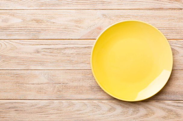Top view of empty yellow plate on wooden background. Empty space for your design. - Photo, Image
