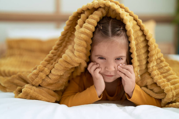 Adorabile ragazza ispanica sdraiato sul letto che copre con lenzuolo in camera da letto - Foto, immagini