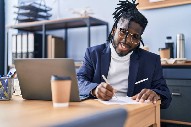 Αφρο-αμερικανίδα επιχειρηματίας που γράφει σε έγγραφο που εργάζεται στο γραφείο - Φωτογραφία, εικόνα