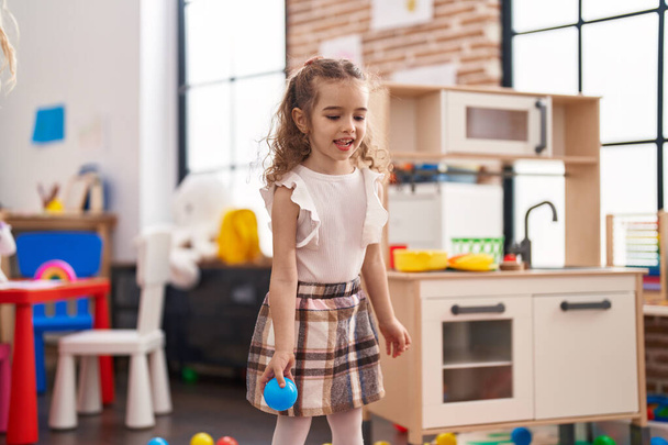 Adorable caucasian girl smiling confident throwing ball at classroom - Photo, Image