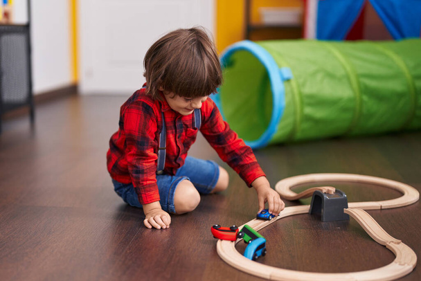 Liebenswertes Kleinkind spielt mit Auto-Spielzeug, das zu Hause auf dem Boden sitzt - Foto, Bild