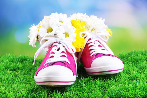 Beautiful gumshoes with flowers inside on green grass, on bright background - Fotó, kép