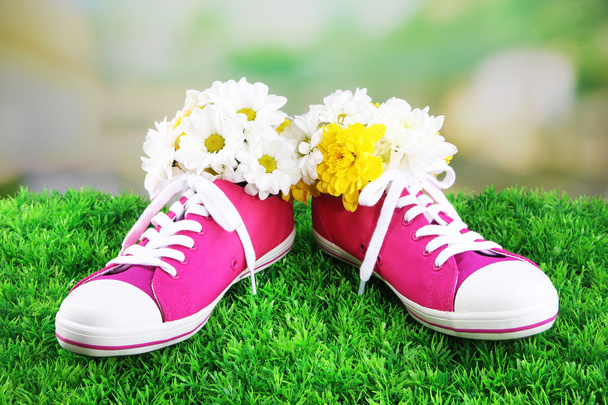 Beautiful gumshoes with flowers inside on green grass, on bright background - Foto, Bild