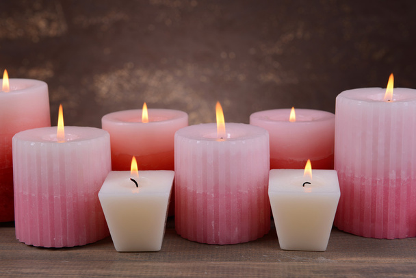 Beautiful candles on table on brown background - Foto, afbeelding