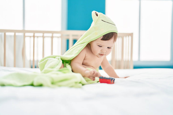 Adorable caucasian baby wearing funny towel playing with car at bedroom - Foto, Bild