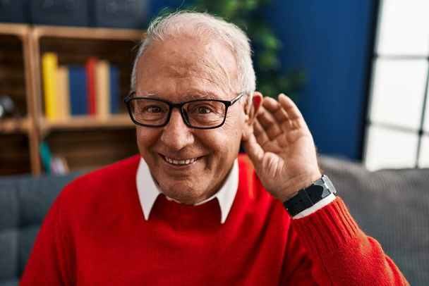 Idősebb férfi mosolyog magabiztos segítségével süketség hallókészülék otthon - Fotó, kép