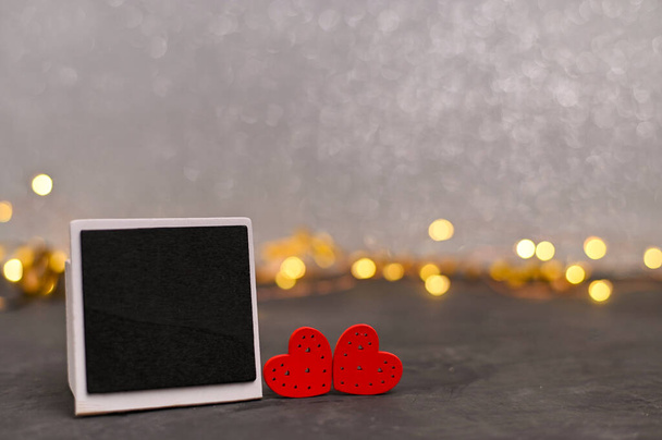 碑文の額を持つ2つの木製の赤い心。バレンタインの日カード。照明付きのボケを背景に - 写真・画像