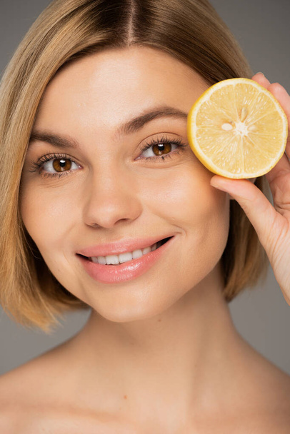 portrait of happy young woman holding fresh lemon isolated on grey  - Photo, image