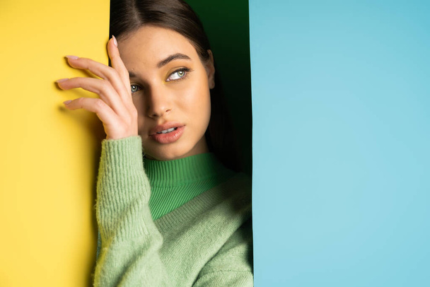 Brunette teenager in jumper touching colorful background  - Foto, Imagen
