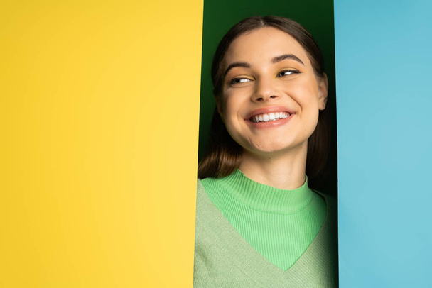 Smiling teenager in jumper looking away on colorful background  - Fotoğraf, Görsel