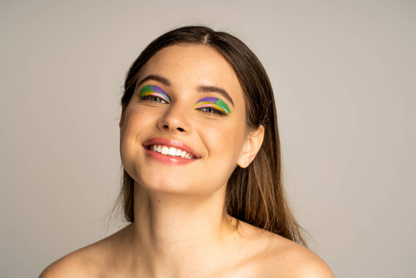 Cheerful teen model with naked shoulders looking at camera isolated on grey  - Photo, Image