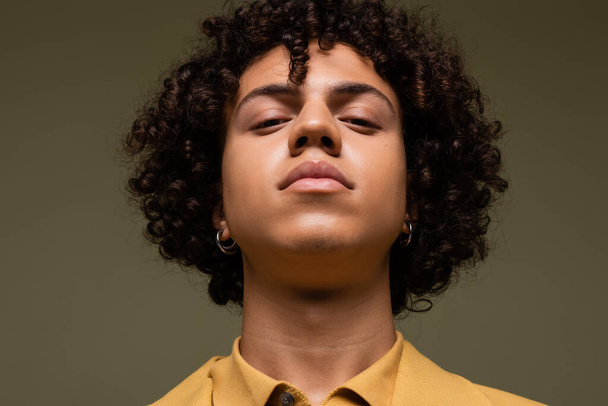 portret van jonge Afrikaanse Amerikaanse man met krullend haar op zoek naar camera geïsoleerd op grijs - Foto, afbeelding