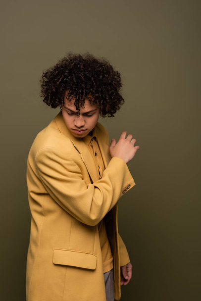 young african american man in stylish yellow jacket posing on grey green background - Zdjęcie, obraz
