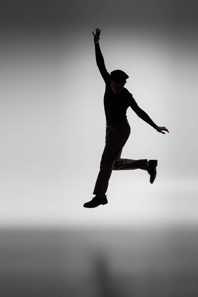 dark silhouette of young african american man jumping on grey background - Foto, Bild