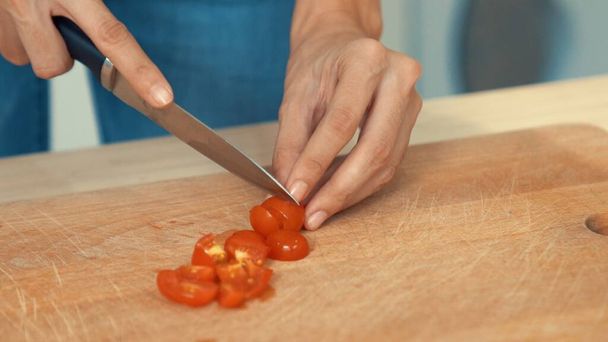 Close up hands holding a knife preparing a contented meal. Sliced tomatoes and other vegetables on the glass dish. - Foto, Bild