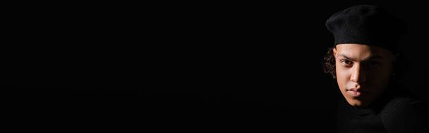 portret młodego Afroamerykanina w ciemnym berecie patrzącego na kamerę odizolowaną na czarno z przestrzenią do kopiowania, baner - Zdjęcie, obraz