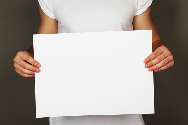 Blank sheet of paper in male hands on dark background - Фото, зображення